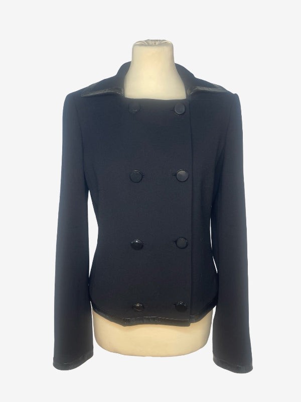A black double-breasted jacket with notched lapels and large dark buttons, displayed on a cream-colored mannequin torso against a light gray background.