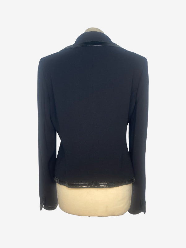A black long-sleeve blazer shown from the back on a cream-colored dress form mannequin against a white background.