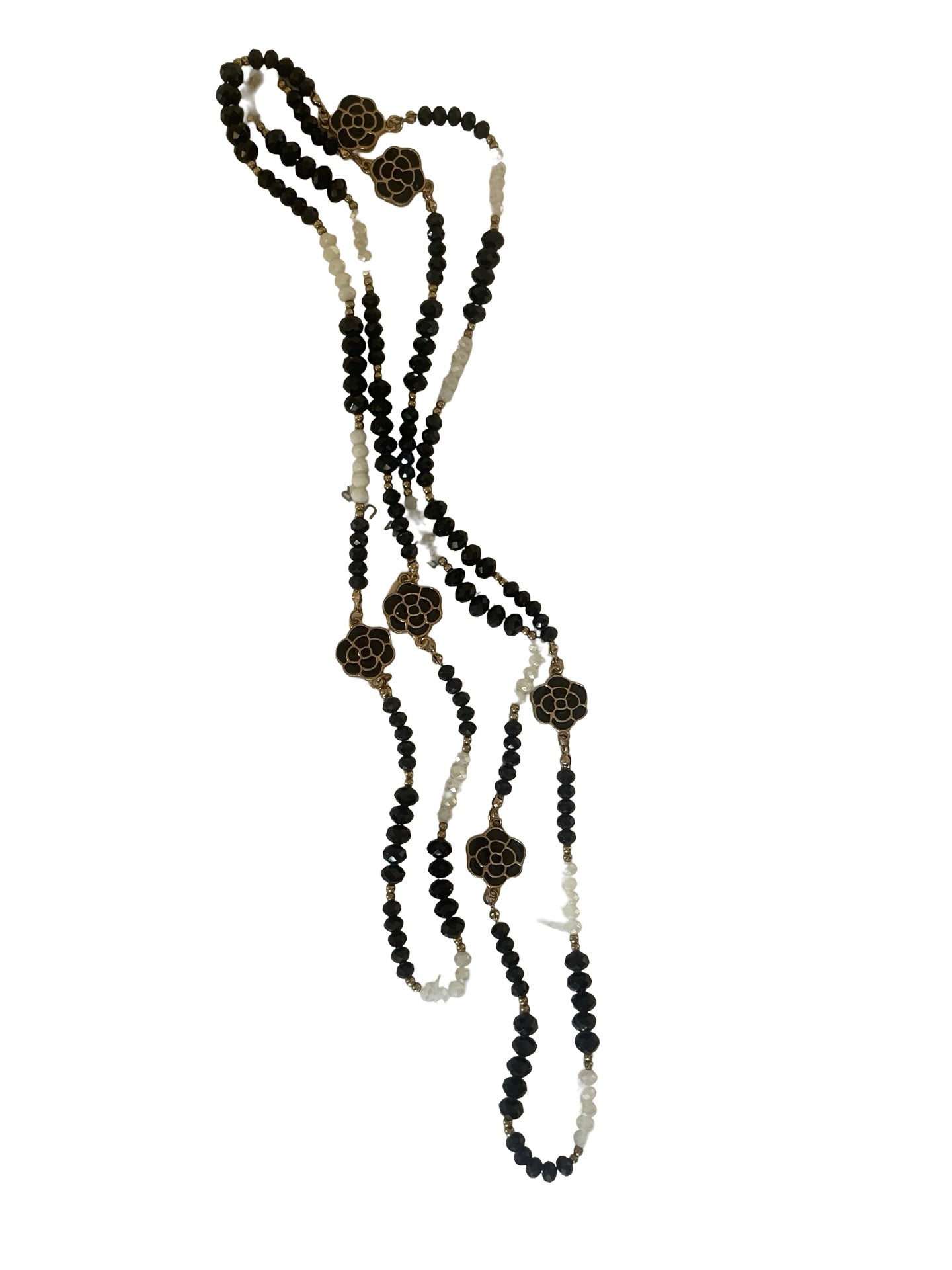 A long beaded necklace with black faceted beads, light cream beads, and brown geometric star-shaped charms, displayed on a solid white background.