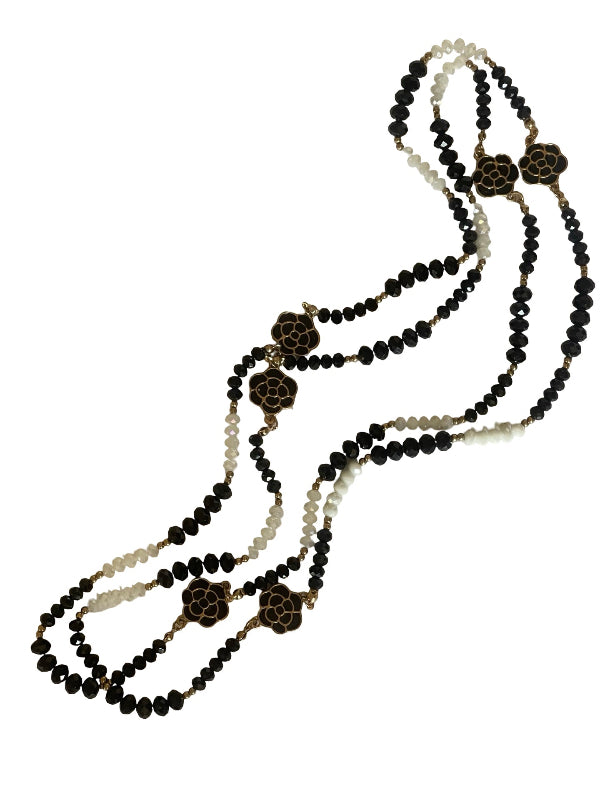 A multi-strand beaded necklace featuring black faceted beads, cream-colored beads, and gold-toned turtle shell charms, displayed on a clean white background.