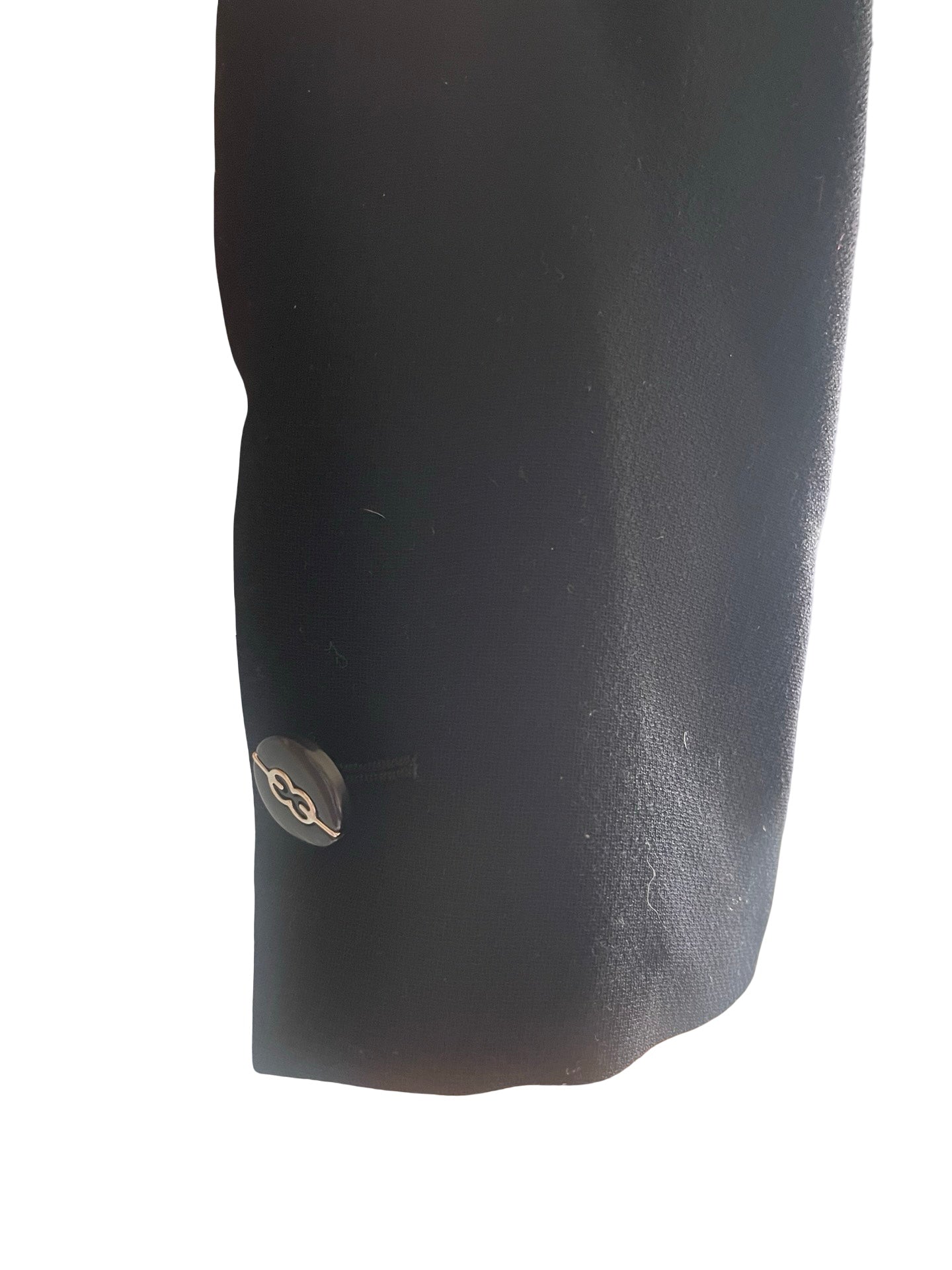 Close-up of a black textured fabric sleeve or cuff with a small metallic button detail, isolated on a white background.