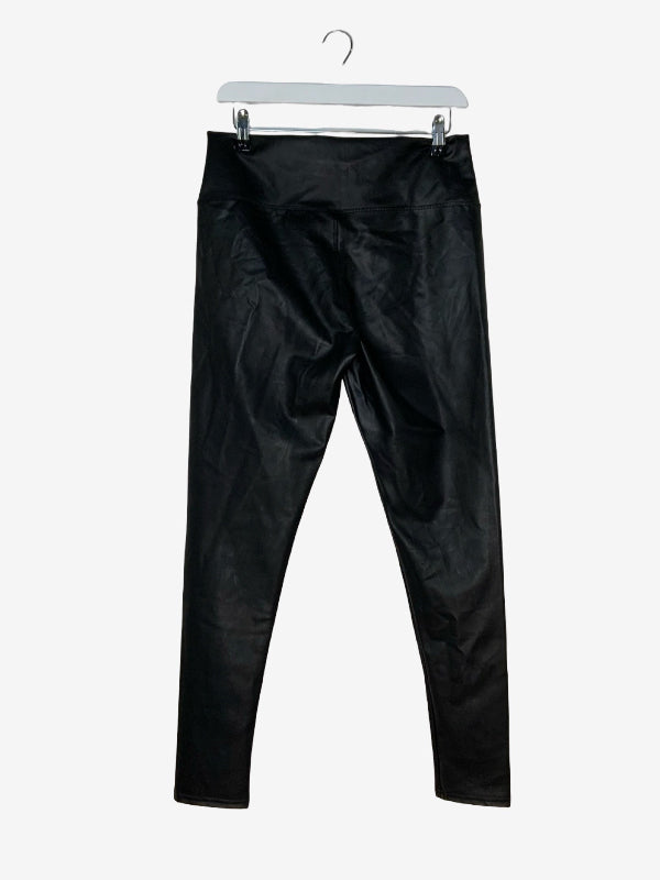 Black faux-leather leggings hanging from a white plastic hanger against a light gray background.