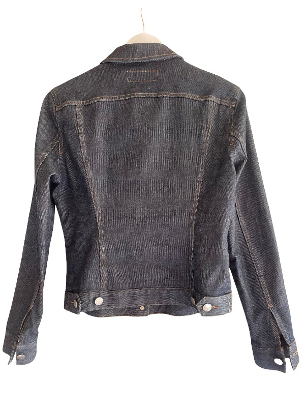 A dark blue washed Italian  denim jacket shown from the back, hanging on a wooden hanger against a plain white background.