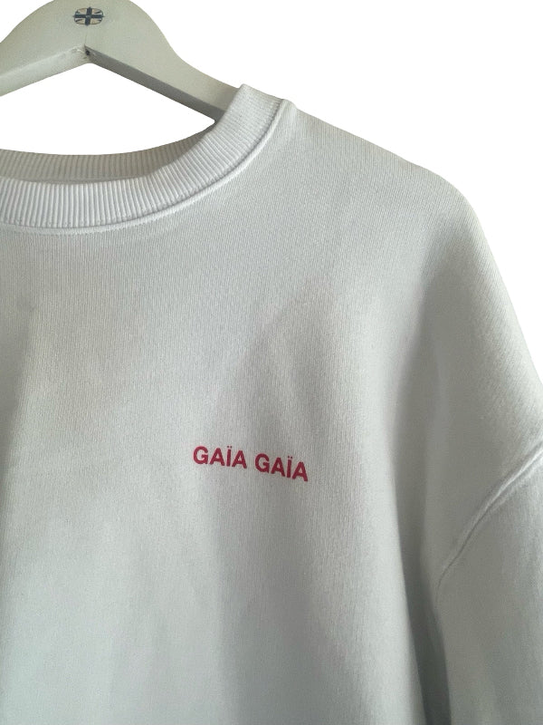 A white crewneck sweatshirt hanging on a white hanger, featuring the word 'GAÍA' embroidered in red on the chest.