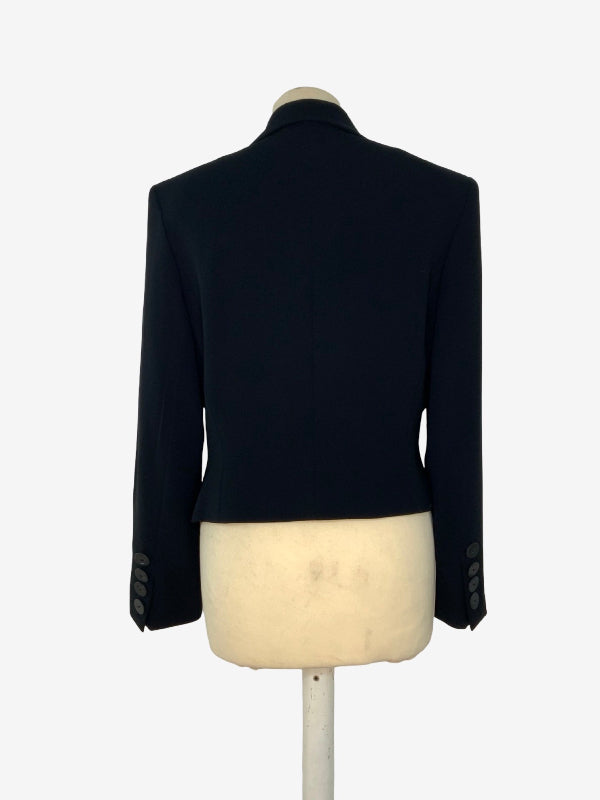 A black tailored blazer shown from the back, displayed on a cream-colored mannequin torso against a plain white background.