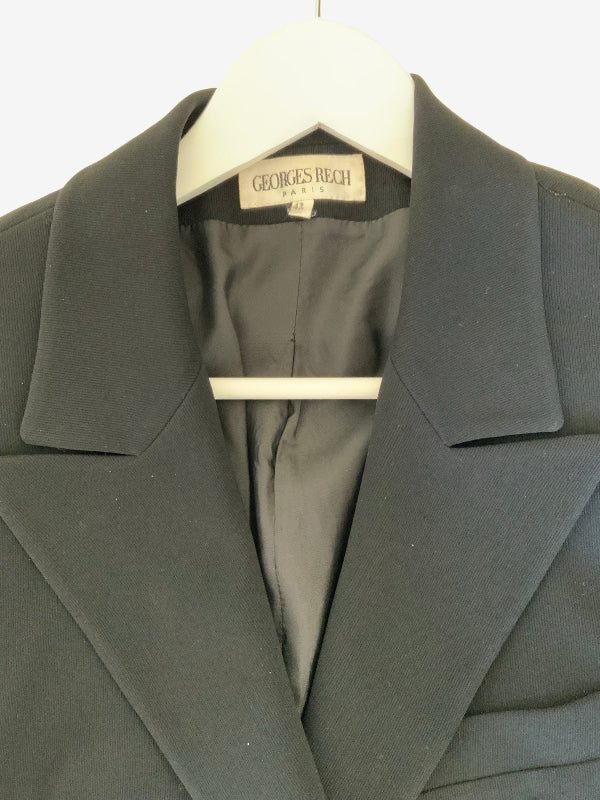 A close-up of a black jacket hanging on a white hanger, showing the collar, lapels, and interior lining with a visible Georges Rech Paris label.