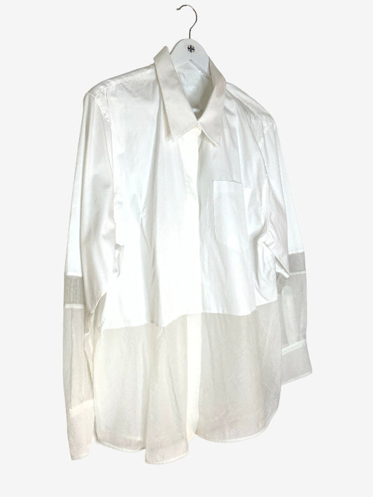 A white long-sleeve shirt with a sheer, semi-transparent lower half and matching sheer cuffs, hanging on a white hanger against a light gray background.