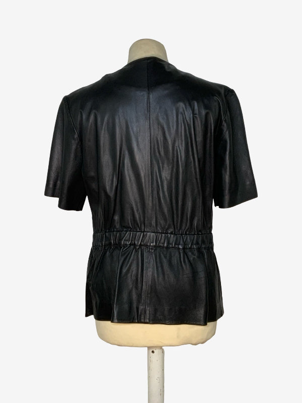 Black leather short-sleeve jacket shown from the back on a mannequin, featuring a gathered peplum waist and a straight neckline, set against a plain white background.