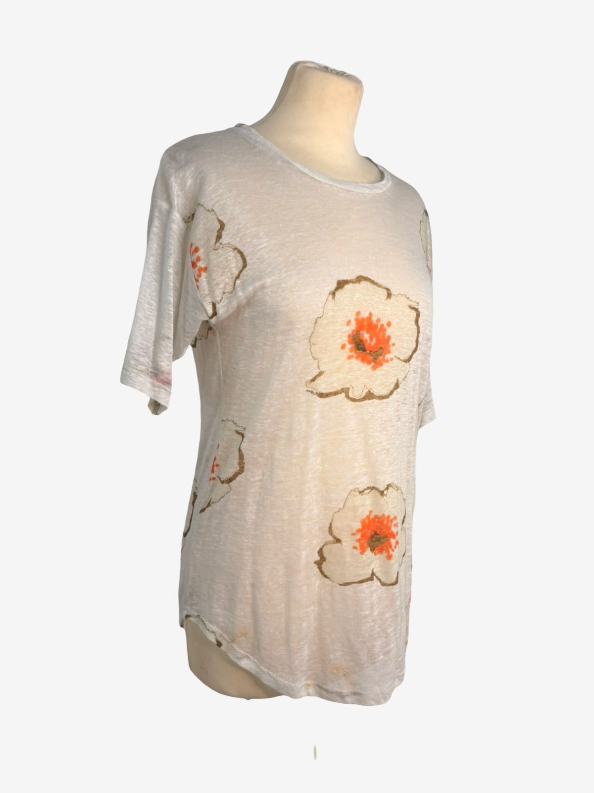 A short-sleeve t-shirt displayed on a mannequin torso against a plain white background. The shirt is a light cream/off-white color with a distressed texture, featuring large hand-painted style flowers in brown outlines with orange centers.