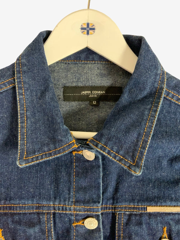 Close-up of a blue denim jacket hanging on a cream hanger against a light background. The collar label reads ‘Jasper Conran Jeans' and '12'.