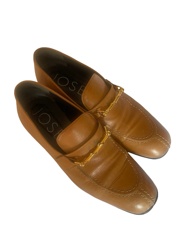 A pair of tan leather loafers with a gold-tone chain detail across the vamp, shown on a plain white background. The brand name 'JOSEPH' is visible on the insole.