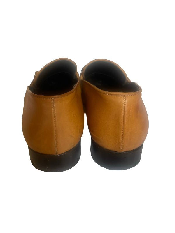 A pair of ladies  casual leather shoes shown from the back, featuring a tan/caramel brown upper and a black sole, set against a plain white background.