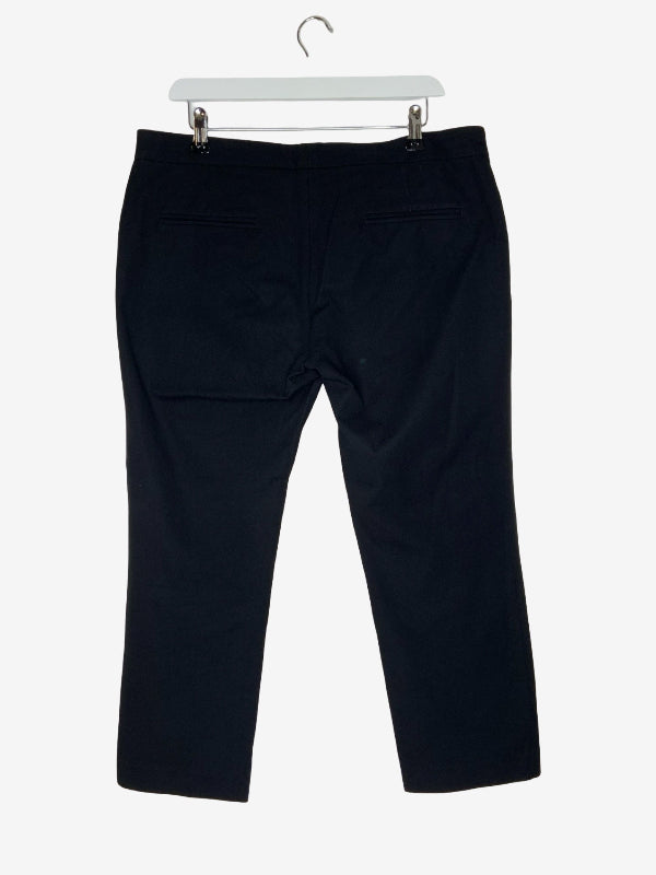 Black cropped trousers shown from the back, hanging from a white plastic hanger against a light gray background.