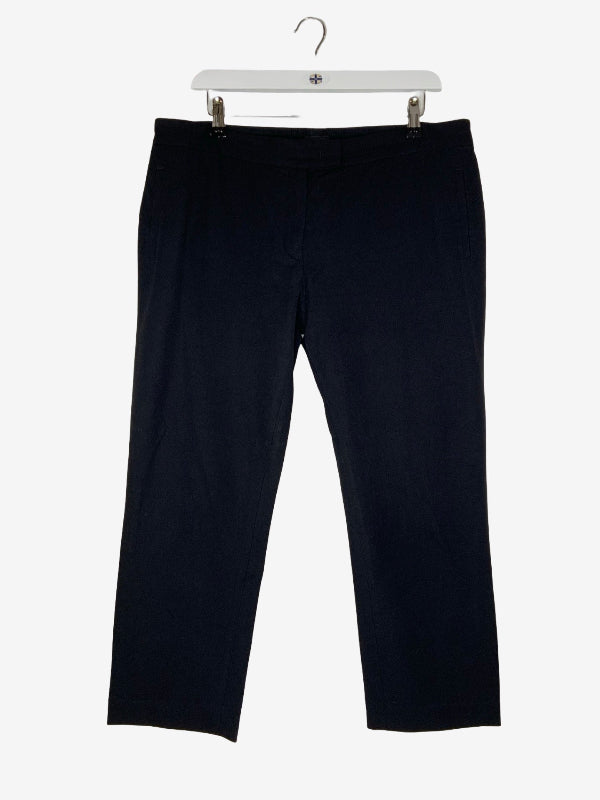A pair of black cropped pants hanging from a white plastic hanger against a light gray background.