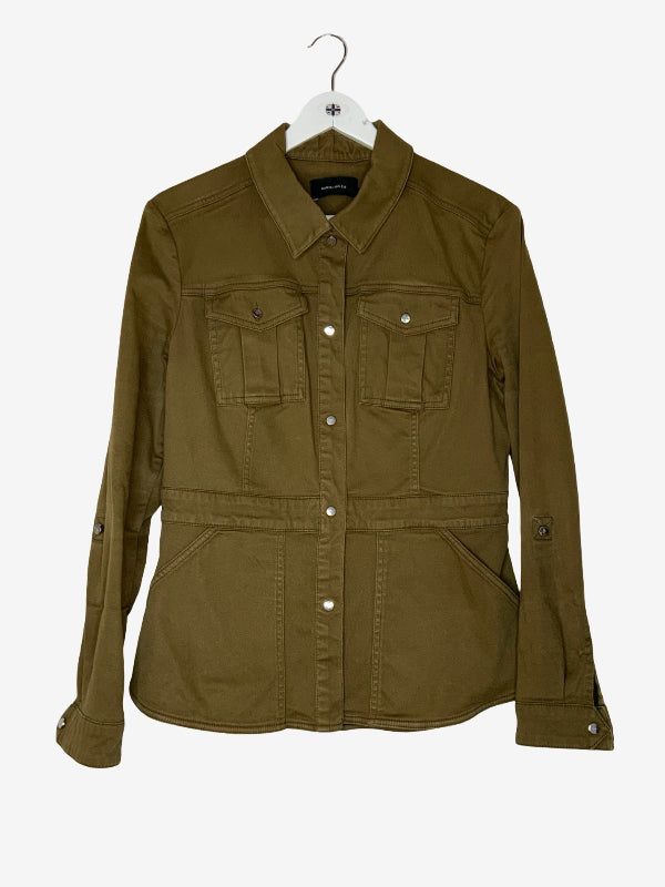 An olive green utility jacket with a pointed collar, button-up front, and four front pockets, hanging on a white hanger against a light gray background.