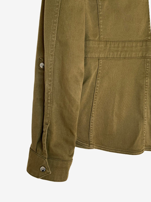 Close-up of an olive green jacket sleeve with a buttoned cuff and a matching horizontal seam detail on the body, shown against a plain light gray background.