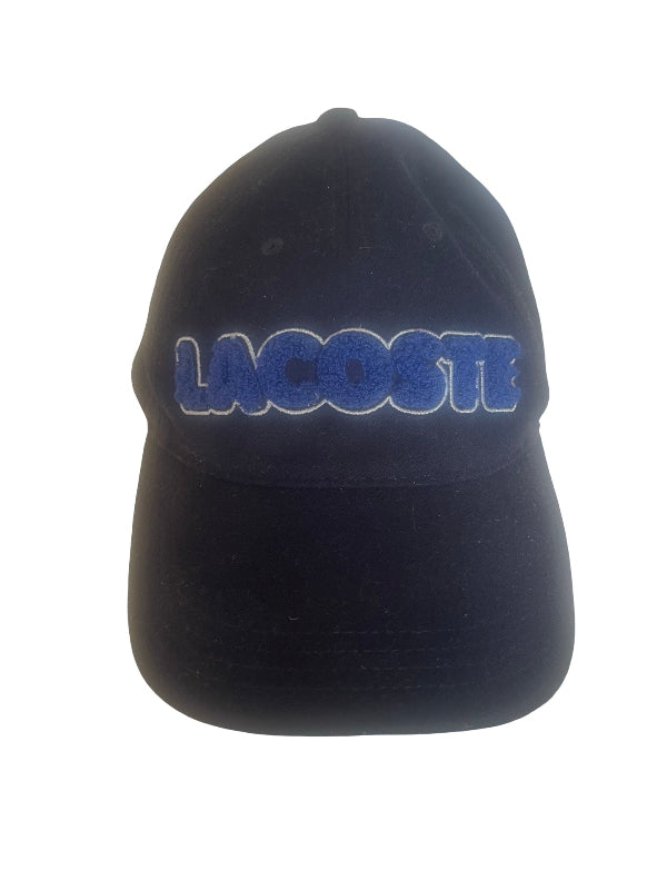 A navy Lacoste baseball cap featuring the brand name embroidered in blue with a white outline across the front panels, set against a plain white background.