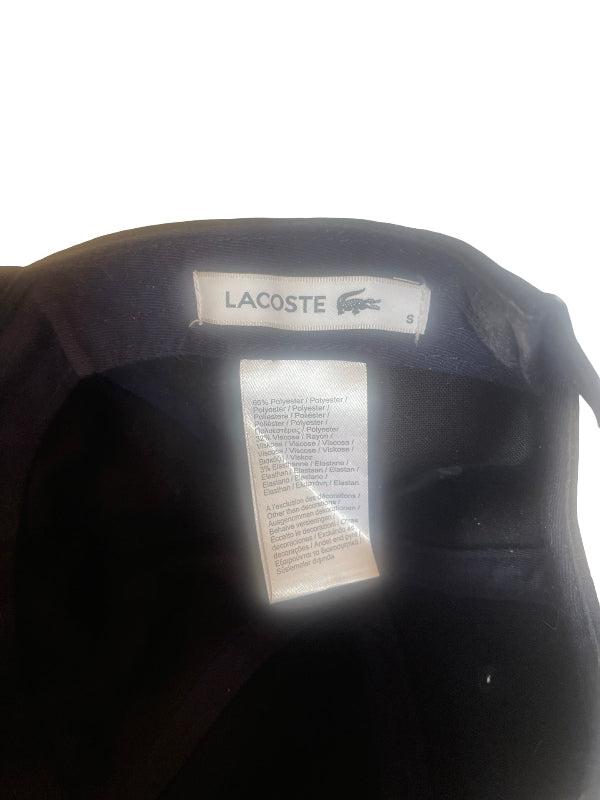 Close-up of the inside collar of a Lacoste garment, showing the Lacoste brand label and a size/care instruction tag against a white background.