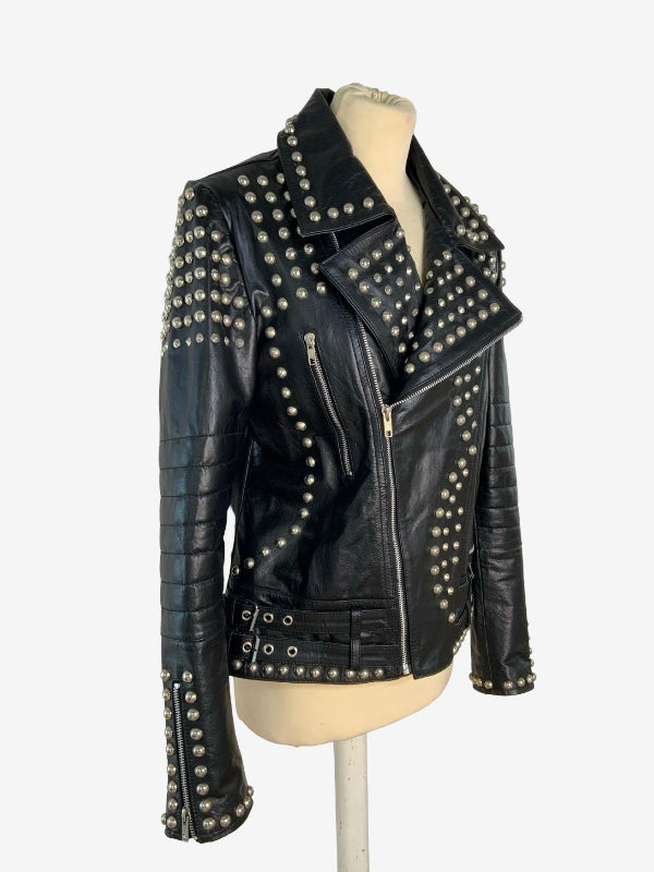 A black leather motorcycle jacket heavily embellished with silver studs, displayed on a beige mannequin torso against a plain white background.