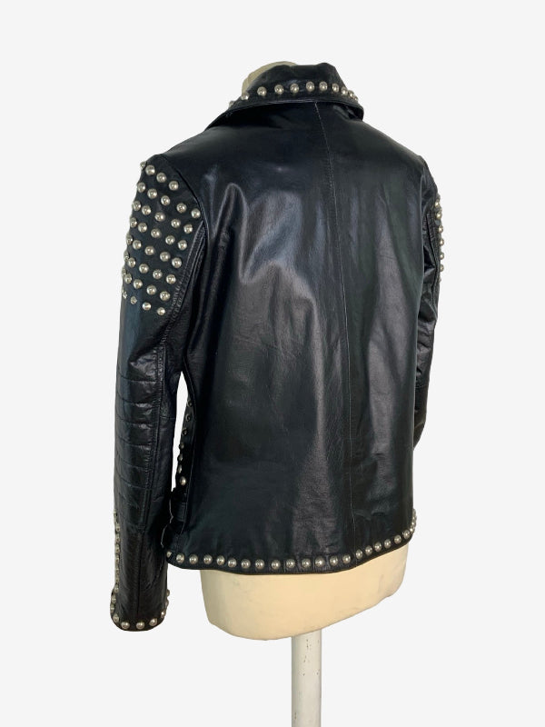 Black leather jacket with silver studs on the shoulders, sleeves, collar, and hem, displayed on a cream mannequin torso against a white background.