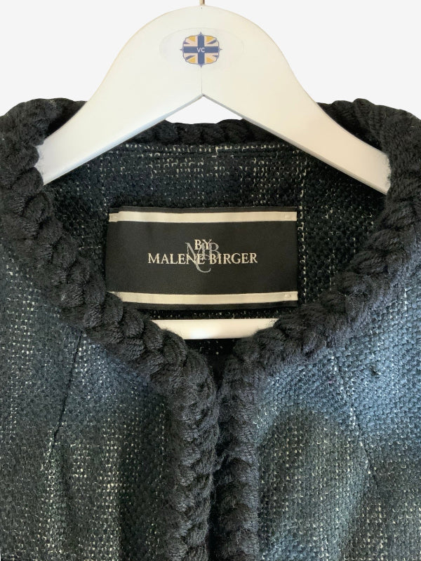 Close-up of a dark gray textured tweed jacket with a chunky braided trim, hanging on a white hanger with a visible Malene Birger label.