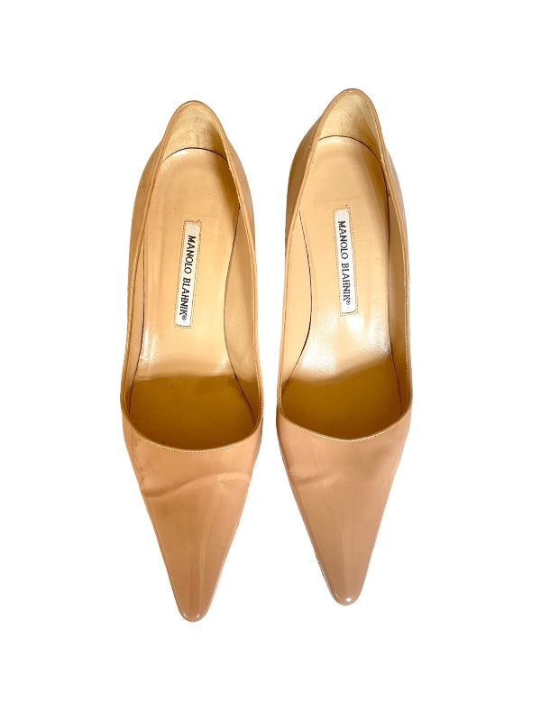 A pair of pointed-toe pumps in a glossy nude beige color, shown from a top-down view on a white background. The brand name 'MANOLO BLAHNIK' is clearly visible on the inner labels.
