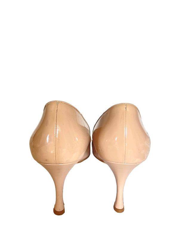 A pair of beige patent leather high-heeled pumps shown from the back, featuring a pointed toe and slim kitten heels, set against a plain white background.