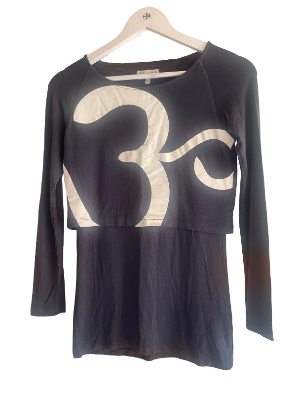 A long-sleeve top on a wooden hanger, featuring a dark blue gray body with a large cream-colored abstract graphic print across the chest and a peplum hem.