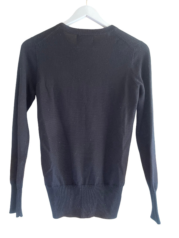 A black wool  knit sweater hanging on a white hanger against a plain white background.