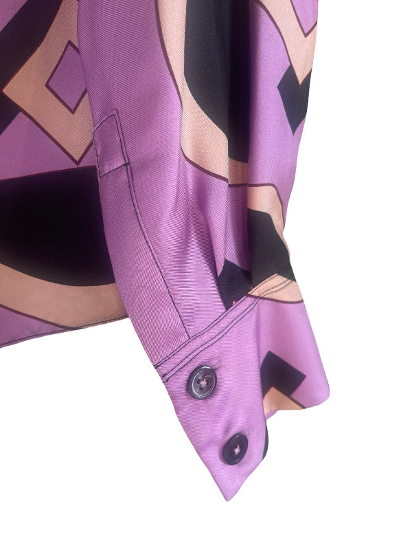 Close-up of a purple long-sleeve button-up shirt with a geometric abstract print in black, beige, and purple, featuring a buttoned cuff.