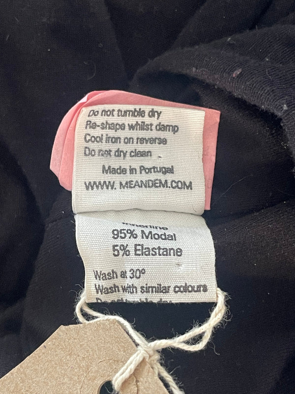 Close-up of a garment's interior care labels attached to a brown paper hangtag, showing fabric composition and care instructions.