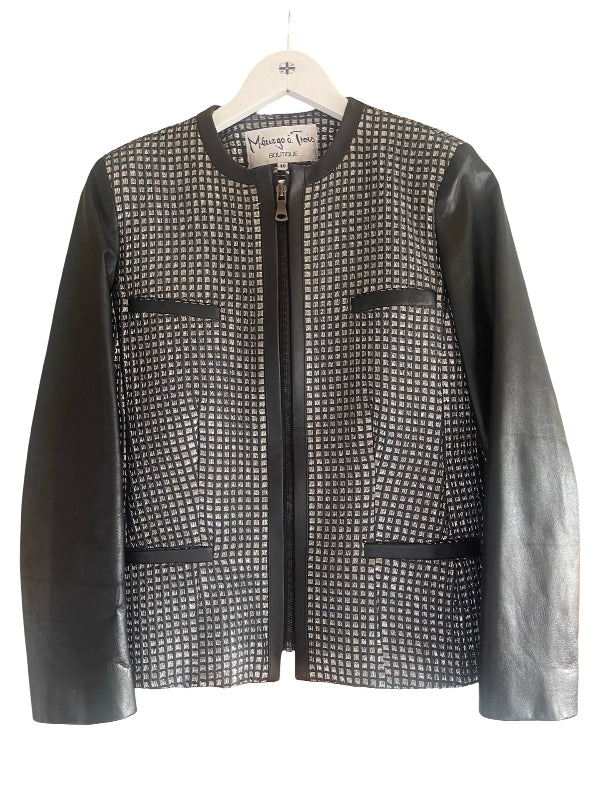 A women's zip-front jacket with a black and white micro-check metallic patterned body and smooth black faux leather sleeves, hanging on a white hanger against a white background.