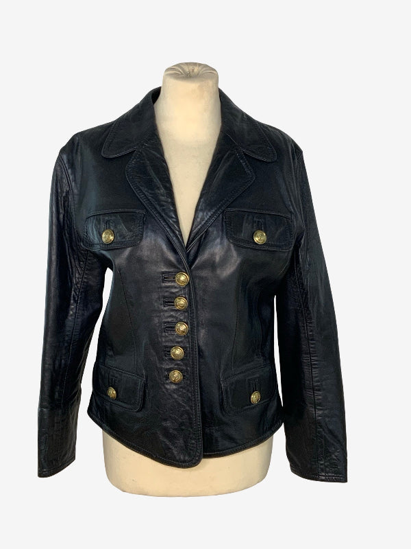 A black leather jacket with gold-tone buttons, displayed on a beige mannequin torso against a light gray background.