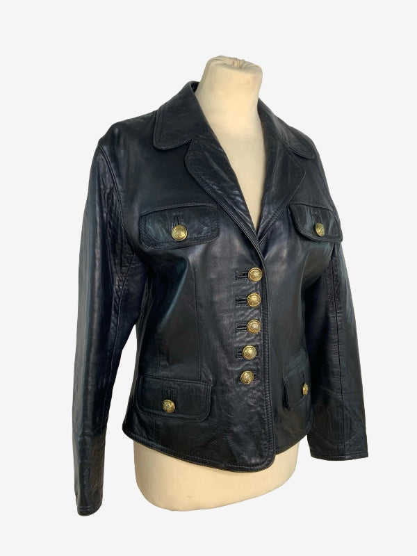 A black leather jacket with gold-tone buttons, displayed on a beige mannequin torso against a light gray background.