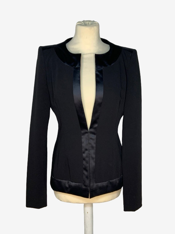 A black long-sleeve blazer with a satin collar and a satin front placket, displayed on a cream-colored dress form mannequin against a light gray background.