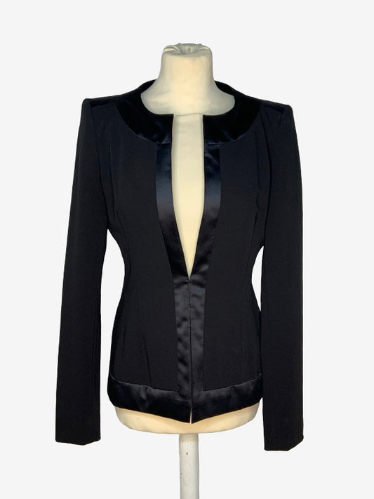 A black long-sleeve blazer with a satin collar and a satin front placket, displayed on a cream-colored dress form mannequin against a light gray background.