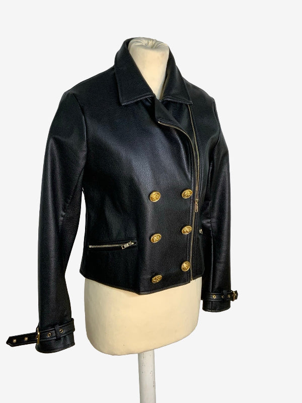 A black faux-leather cropped jacket with gold-tone hardware, displayed on a cream mannequin torso against a light gray background.