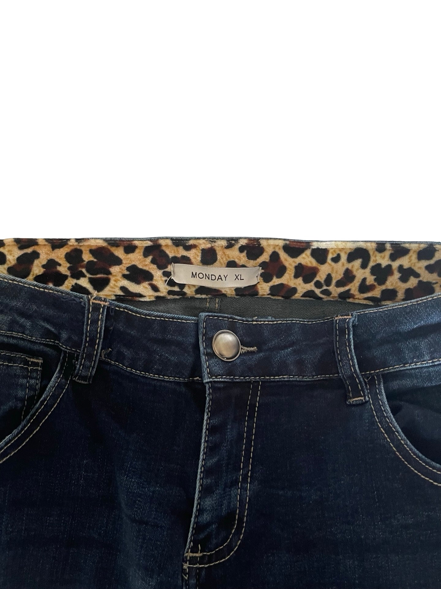Close-up of the waistband of dark blue denim jeans with a leopard print inner lining and a visible 'MONDAY XL' size label.