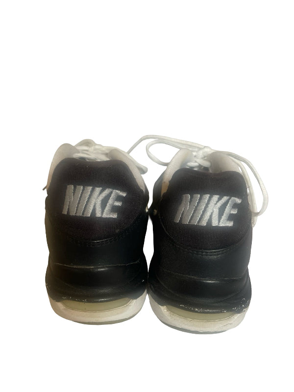 A pair of black Nike sneakers viewed from the back, featuring white 'NIKE' logos on the heel tabs and white laces, set against a plain white background.