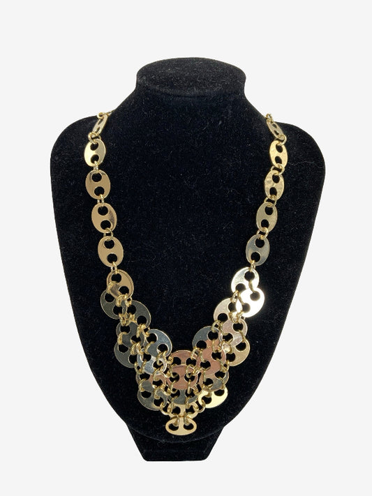 A chunky statement necklace made of interlocking circular links in gold and silver tones, displayed on a black velvet jewelry bust against a light gray background.