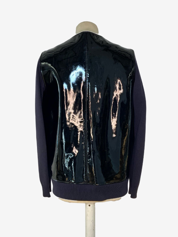 A dark navy blue sleeve jacket with a glossy, high-shine black patent leather  back panel, displayed on a mannequin against a light gray background.