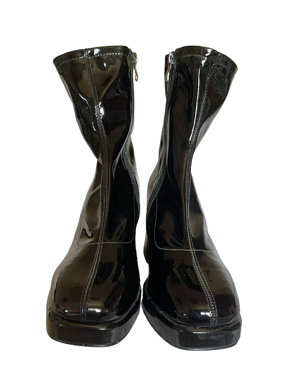 A pair of glossy black patent leather ankle boots with side zippers, shown from the front against a plain white background.