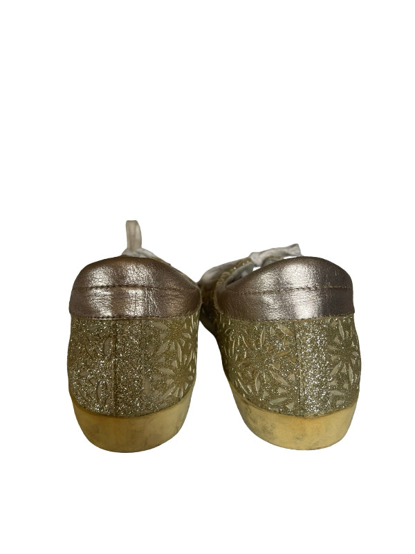 A pair of low-top casual shoes with metallic gold uppers and textured gold glittery patterned sides, shown from the back on a white background.
