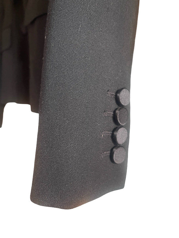 Close-up of a black textured wool fabric sleeve with four dark covered buttons, set against a solid white background.