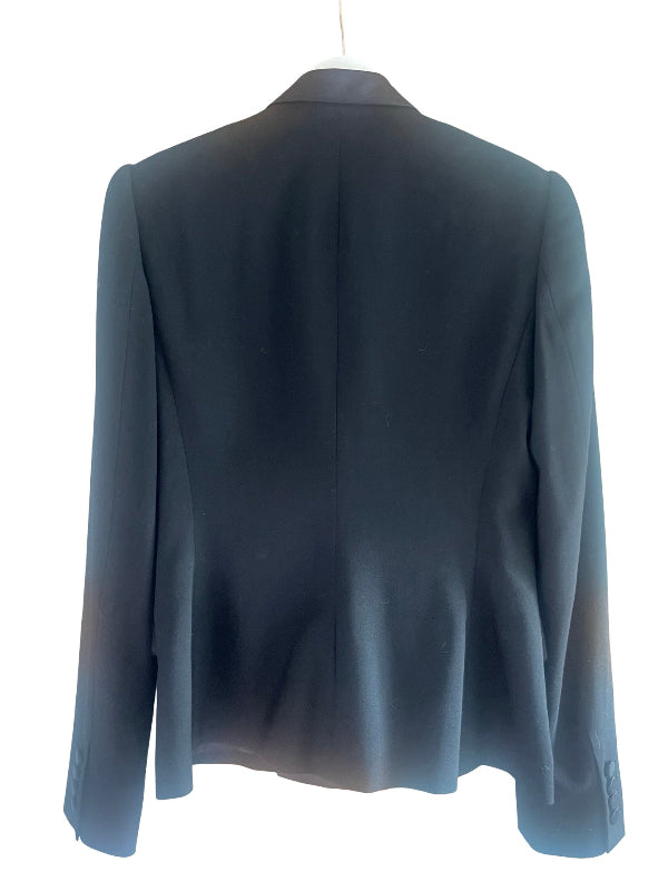 A dark black blazer shown from the back, hanging on a white hanger against a plain white background.