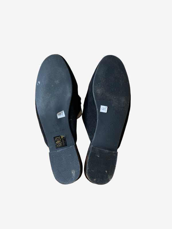 The soles of a pair of black shoes, showing the tread and a small gold brand label that reads 'BARRA', photographed against a plain white background.