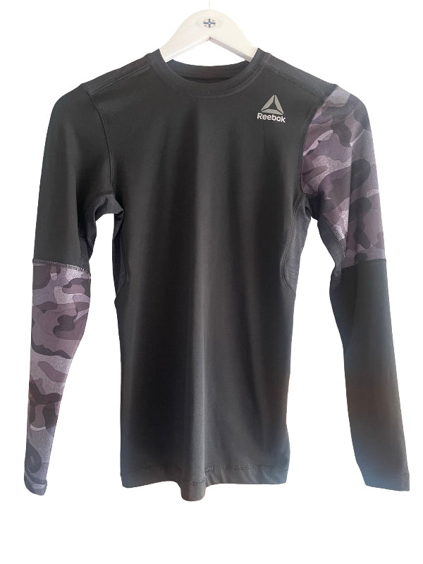 A long-sleeve athletic shirt by Reebok, featuring a solid dark gray body and gray camouflage sleeves, hanging on a white hanger against a white background.