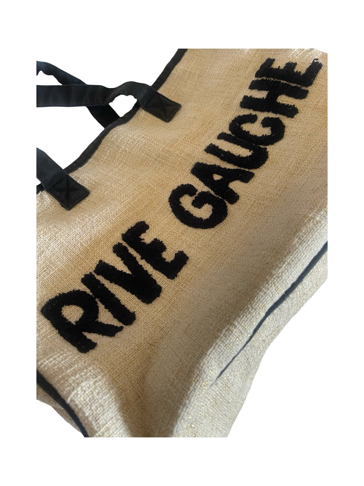A close-up of a beige woven tote bag with black handles and black text reading 'RIVE GAUCHE' on a white background.