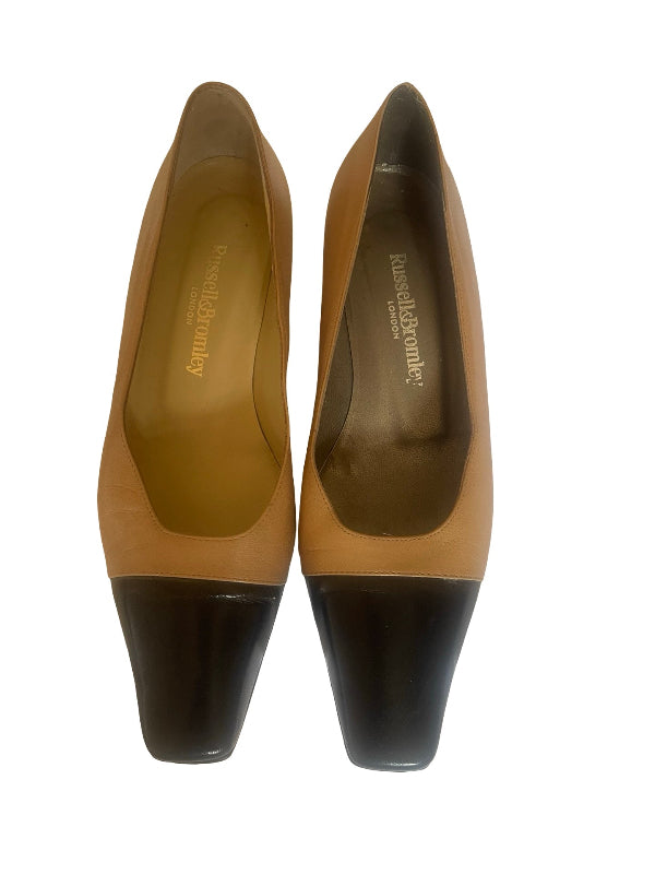 A pair of women's pointed-toe pumps in tan leather with contrasting black block heels, shown from a top-down view on a white background. The insole displays the brand name 'Russell and Bromley'.