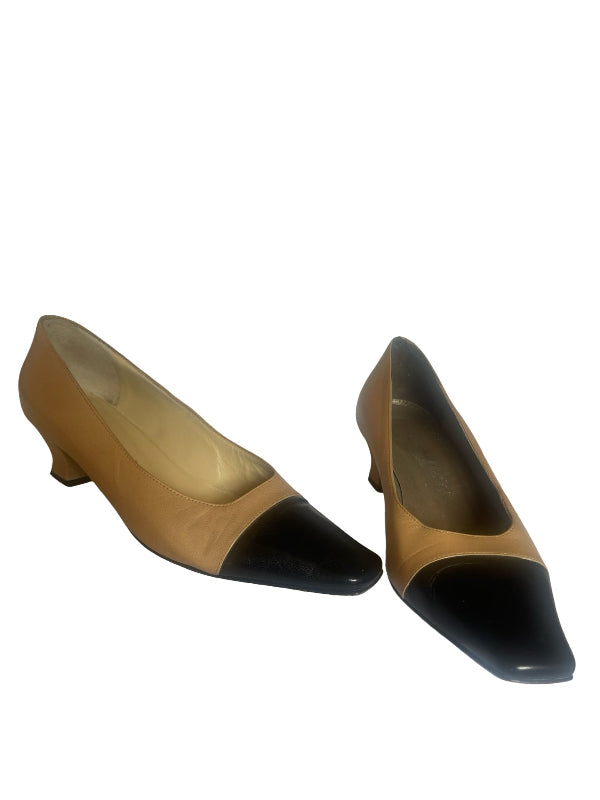 A pair of women's low-heel pumps with a tan leather body and contrasting black pointed toes, shown against a plain white background.